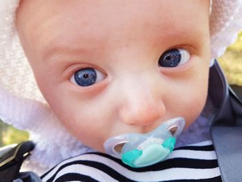 Close-up portrait of cute baby boy sucking pacifier outdoors