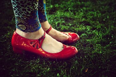 Woman's feet in red shoes on grass