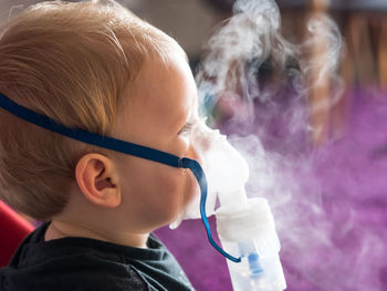 Close-up portrait of cute boy holding camera