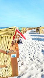 Hooded beach chairs on sand against clear sky