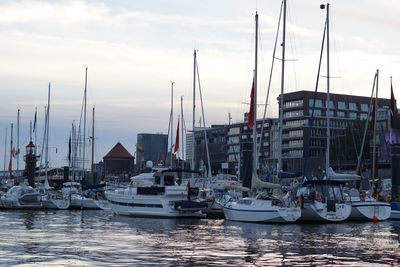 Sailboats moored on harbor against sky
