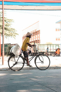 Side view of man riding bicycle on street