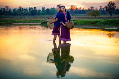Full length of woman on lake against sky during sunset