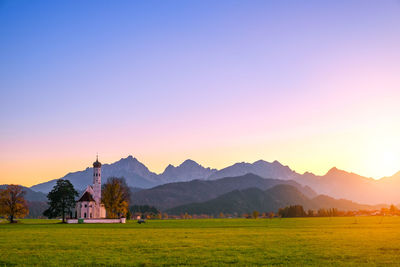 Scenic view of church on landscape against clear sky during sunset