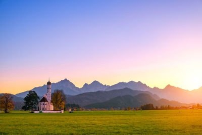 Scenic view of church on landscape against clear sky during sunset