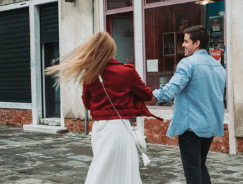 Rear view of couple standing on street against building