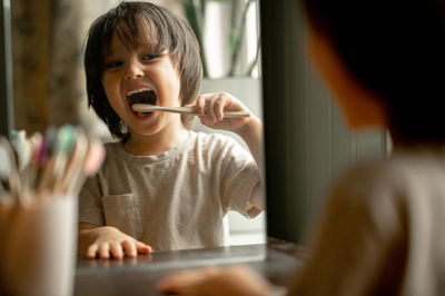 The boy brushes his teeth with a toothbrush made of ecological material