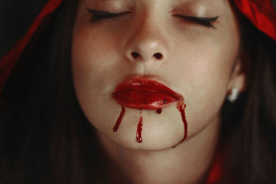 Close-up of beautiful girl with blood on lips during halloween