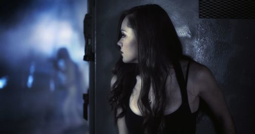 Close-up of young woman peeking by metal