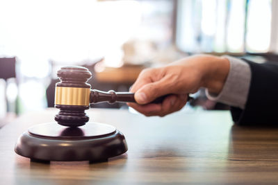 Cropped hand of lawyer holding gavel on desk in office