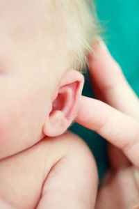 Cropped hand of person touching baby boy ear