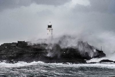 Lighthouse by sea against sky