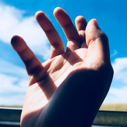 Cropped hand gesturing against sky