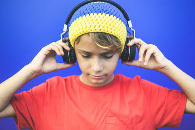 Boy listening to music against blue background