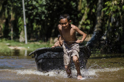 Full length of shirtless man splashing water