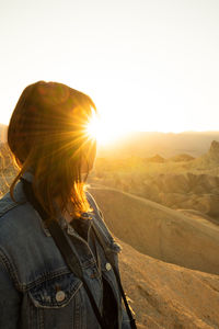 Rear view of woman standing by mountain against clear sky