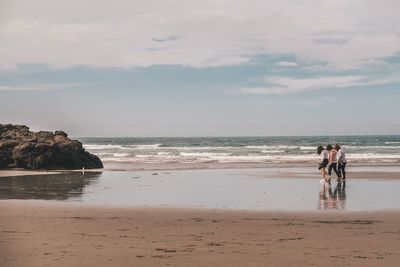 People at beach against sky