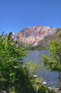 Scenic view of lake and mountains against clear blue sky