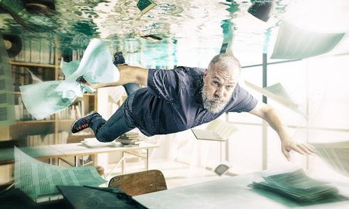 Portrait of man swimming underwater in flooded office