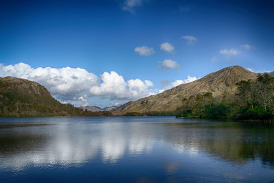 Scenic view of lake and mountains against blue sky