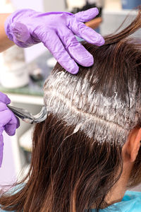 Close-up of hairdresser applying cream on woman head
