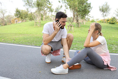 Full length of friends sitting on mobile phone