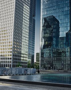 Modern buildings by swimming pool in city against sky