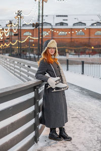 Portrait of young woman standing on railing