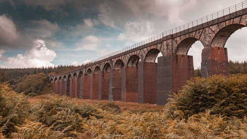 Arch bridge on field against sky