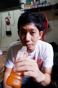Portrait of man having juice from bottle at home