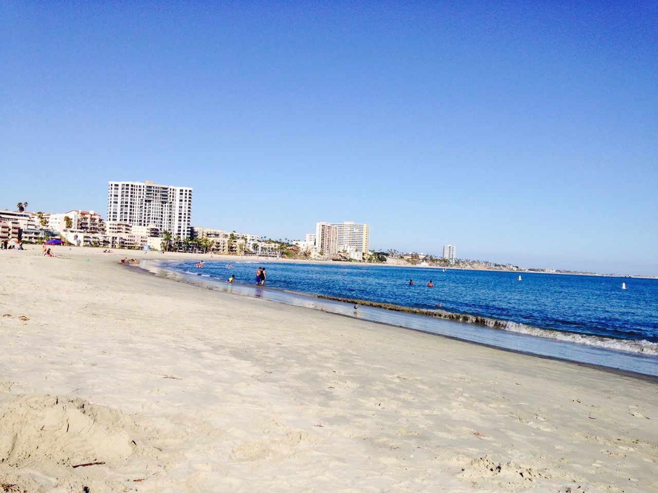 clear sky, sea, copy space, beach, water, architecture, built structure, blue, building exterior, sand, shore, incidental people, coastline, horizon over water, day, mid distance, tranquility, nature, city, outdoors