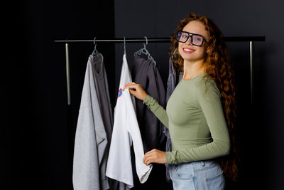 Portrait of young woman standing against wall