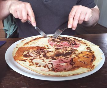 Midsection of man eating pancake in plate