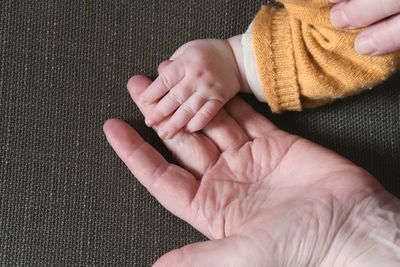 Cropped hands of parent and baby at home