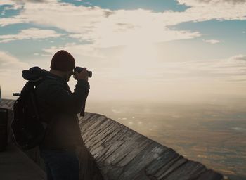 Rear view of man photographing at camera