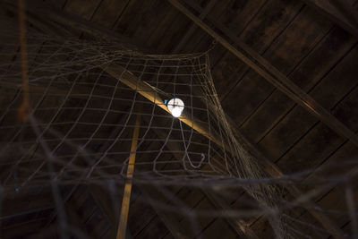 Low angle view of illuminated electric bulb by netting