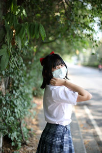 Rear view of girl standing against plants