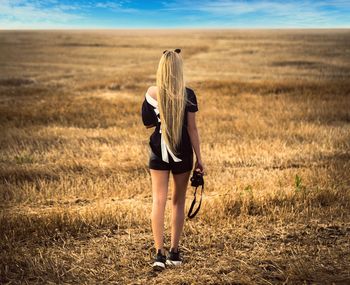 Rear view of woman holding camera while standing on land