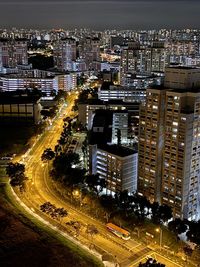 High angle view of illuminated street amidst buildings in city at night