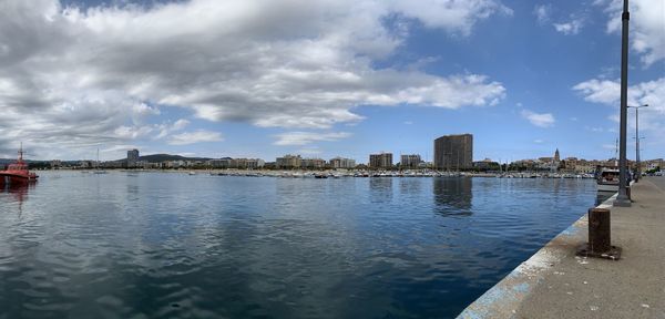 Buildings by river against sky