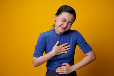 Mid adult man standing against yellow background