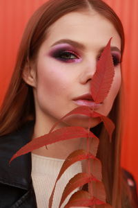 Close-up portrait of young woman holding leaf