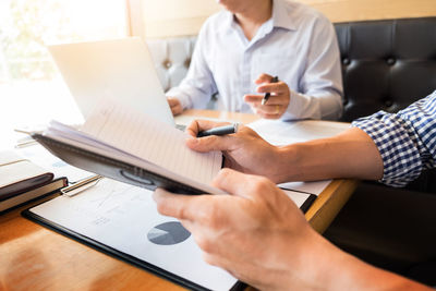 Midsection of woman using mobile phone while sitting on table