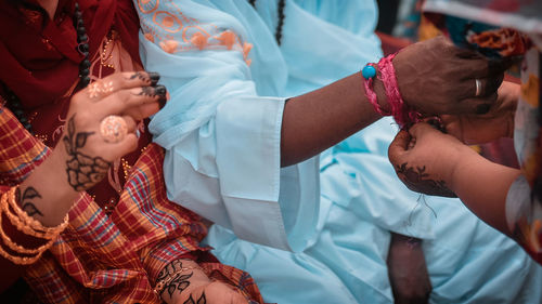 Close up of a woman tying a knot in the groom's hand in a traditional sudanese wedding ceremony 