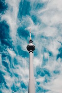 Low angle view of communications tower and building against sky