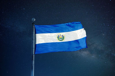 Low angle view of el salvadoran flag against star field sky