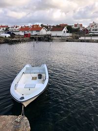 Boat moored on sea by buildings against sky