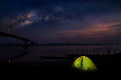 Tent in water against sky at night