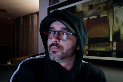 Close-up of man wearing eyeglasses and hood clothing at home