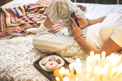 Low section of woman using phone on bed